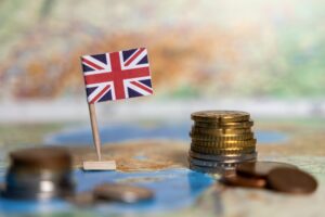 Remittance Base UK: BFH erkennt Vorzugsbesteuerung an - Britische Flagge mit gestapelten Münzen vor einer Landkarte