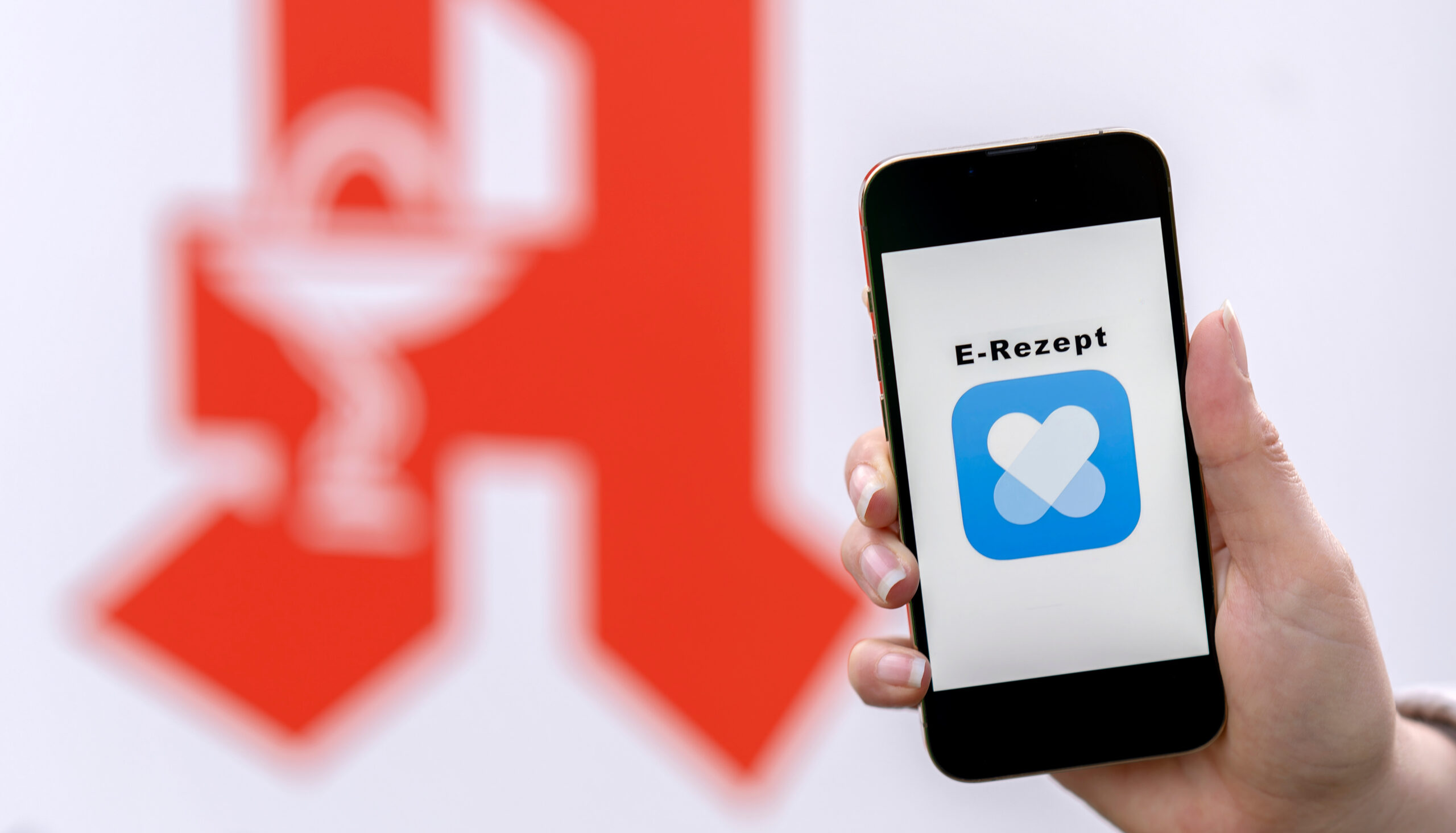 E-Rezept im Apothekenalltag: Rechtliche Risiken kennen und vermeiden - Handy mit E-Rezept vor Apothekenschild