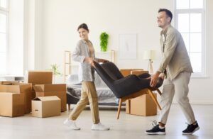 BFH: Ehegatten‑Mietvertrag steuerlich anerkannt - Mann und Frau tragen Stuhl in neuer Wohnung