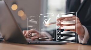 Hände vor Laptop und davor generierte Dokumente mit Checkkästchen.